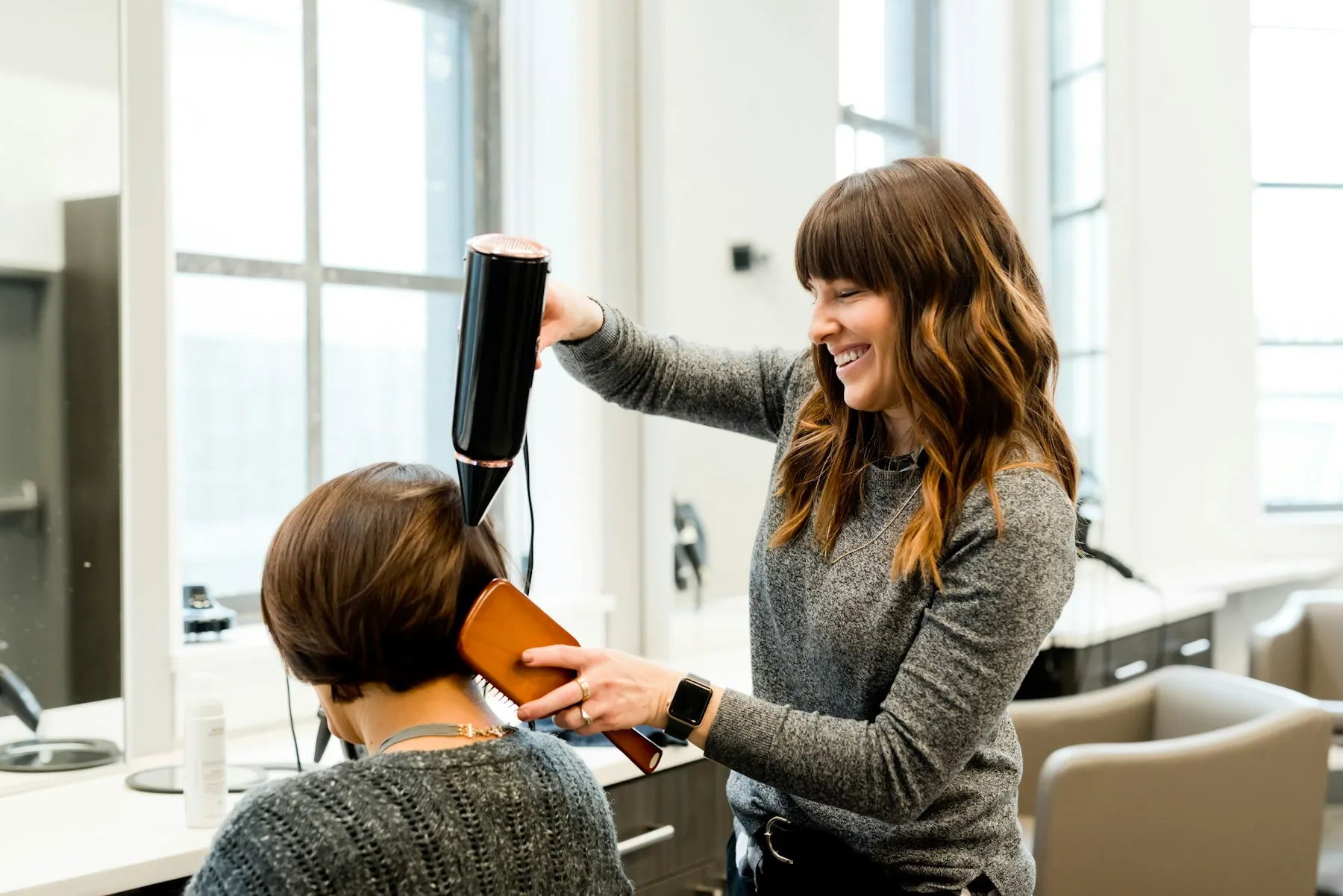 Cabeleireira a secar o cabelo a uma cliente no salão